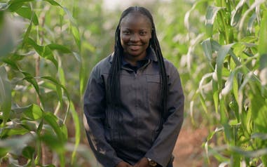Dora Shimbwambwa standing in a field smiling.