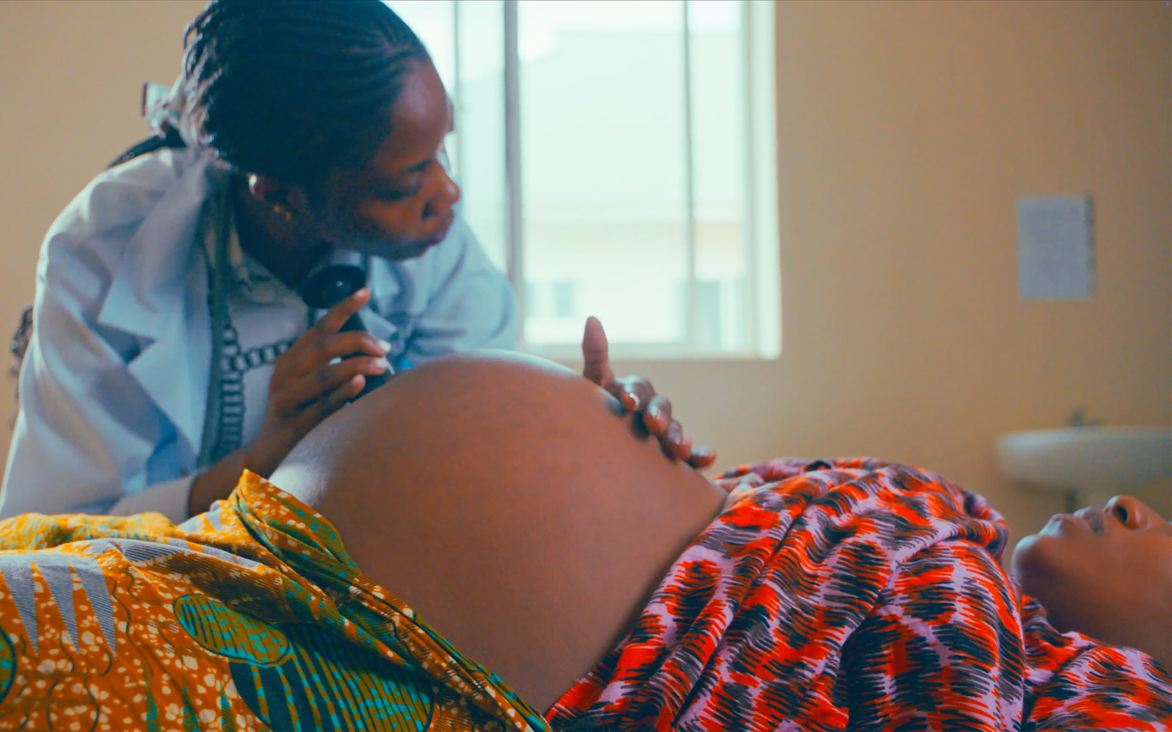 Un operatore sanitario utilizza un fetoscopio sull'addome di una donna incinta.