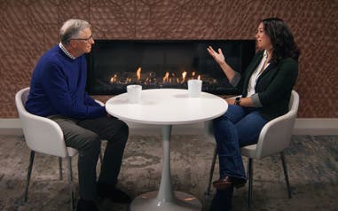 Bill Gates and Blaire Penry, the 2024 Washington State Teacher of the Year, sitting at a table in front of a fireplace talking.