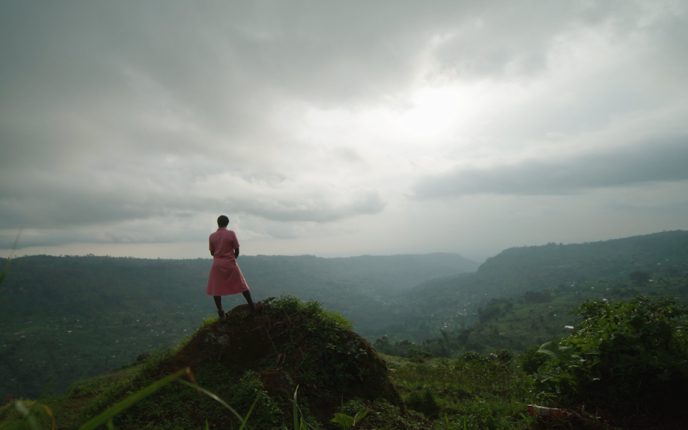 Agnes Nambozo stands at the top of a mountain near a remote village for vaccine outreach in eastern Uganda.