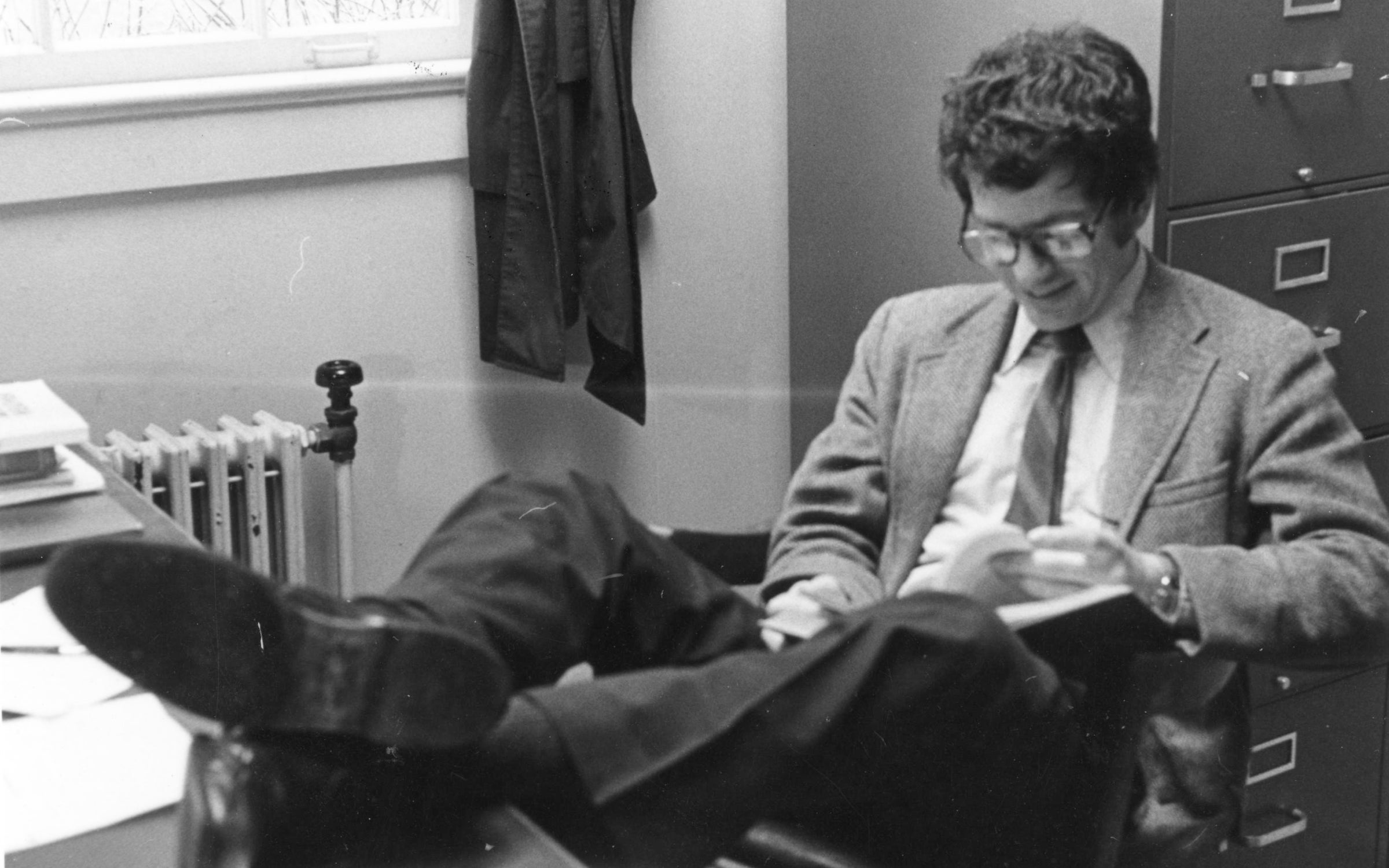 Fred Wright sitting with his feet on a desk looking at a book.