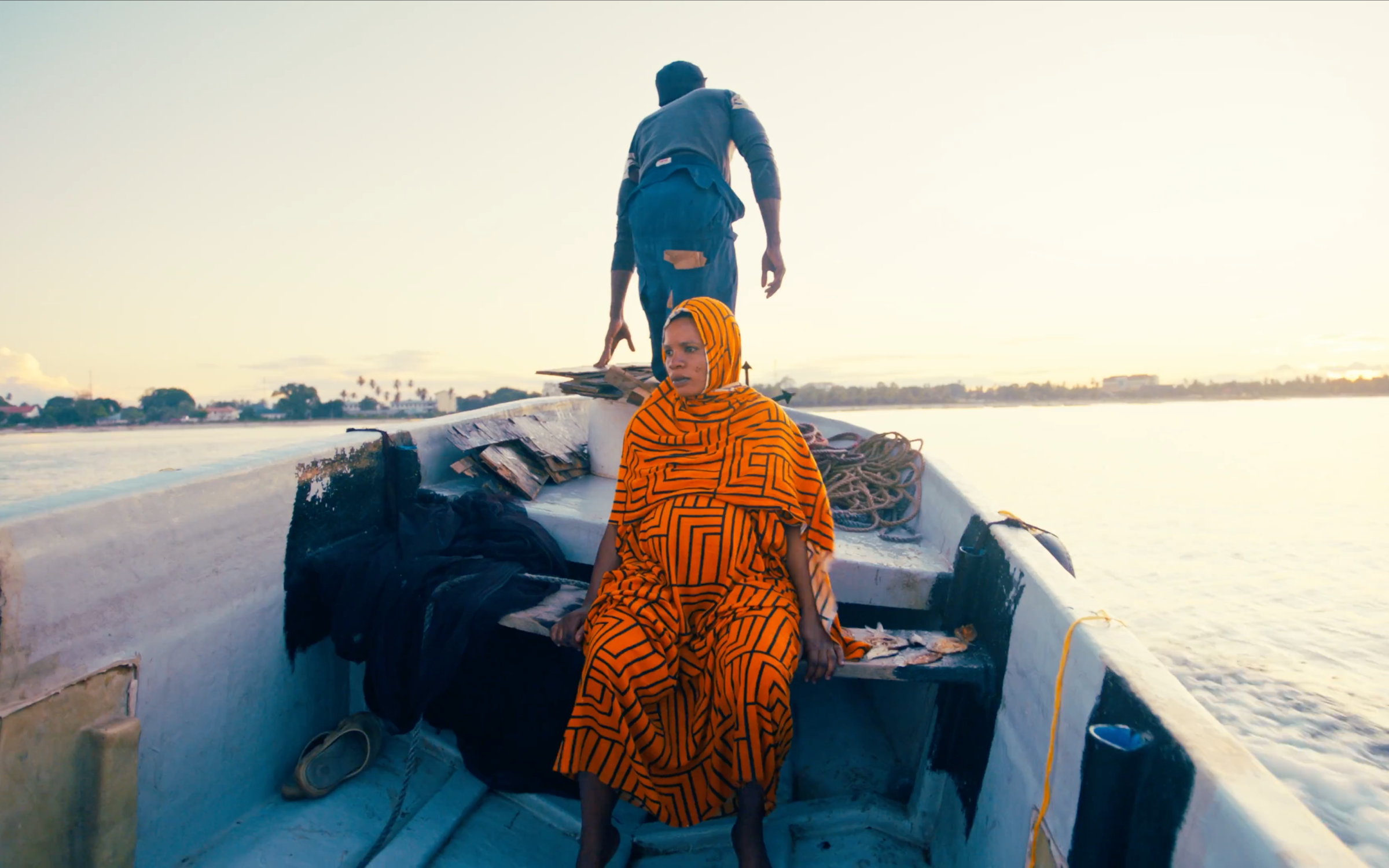 A pregnant woman sitting on a boat with a man behind her.