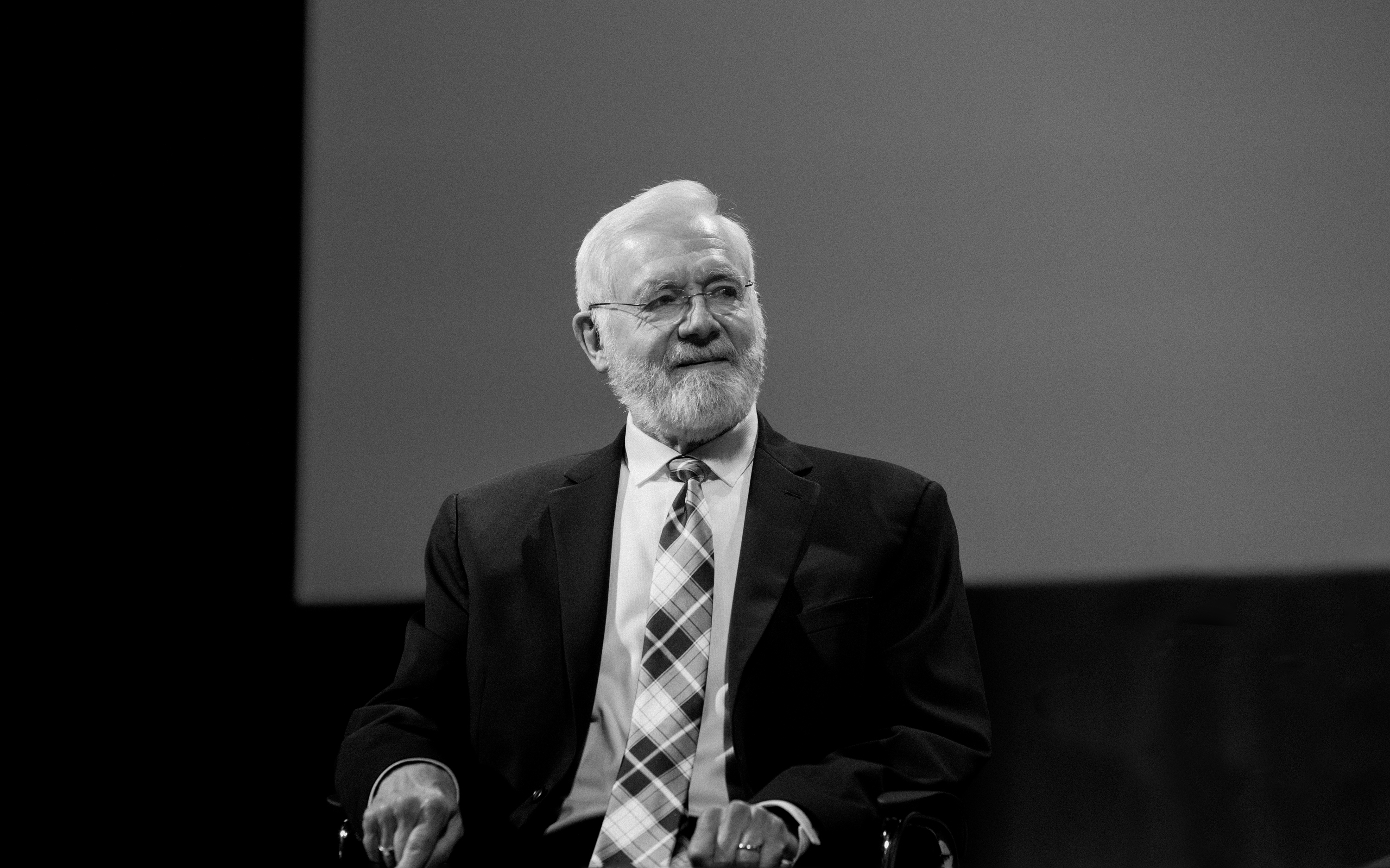 Bill Foege sitting in a chair looking to the side.